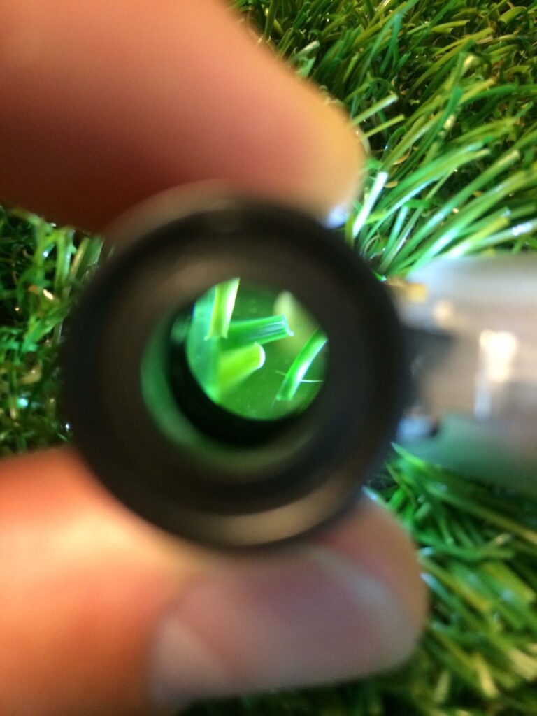 Photo of a artificial grass fibre close up using a magnifying glass. 