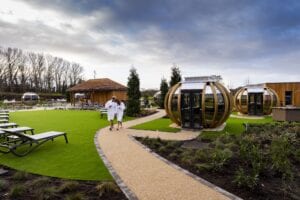 People walking passed the pods in the outdoor area at the Carden park spa
