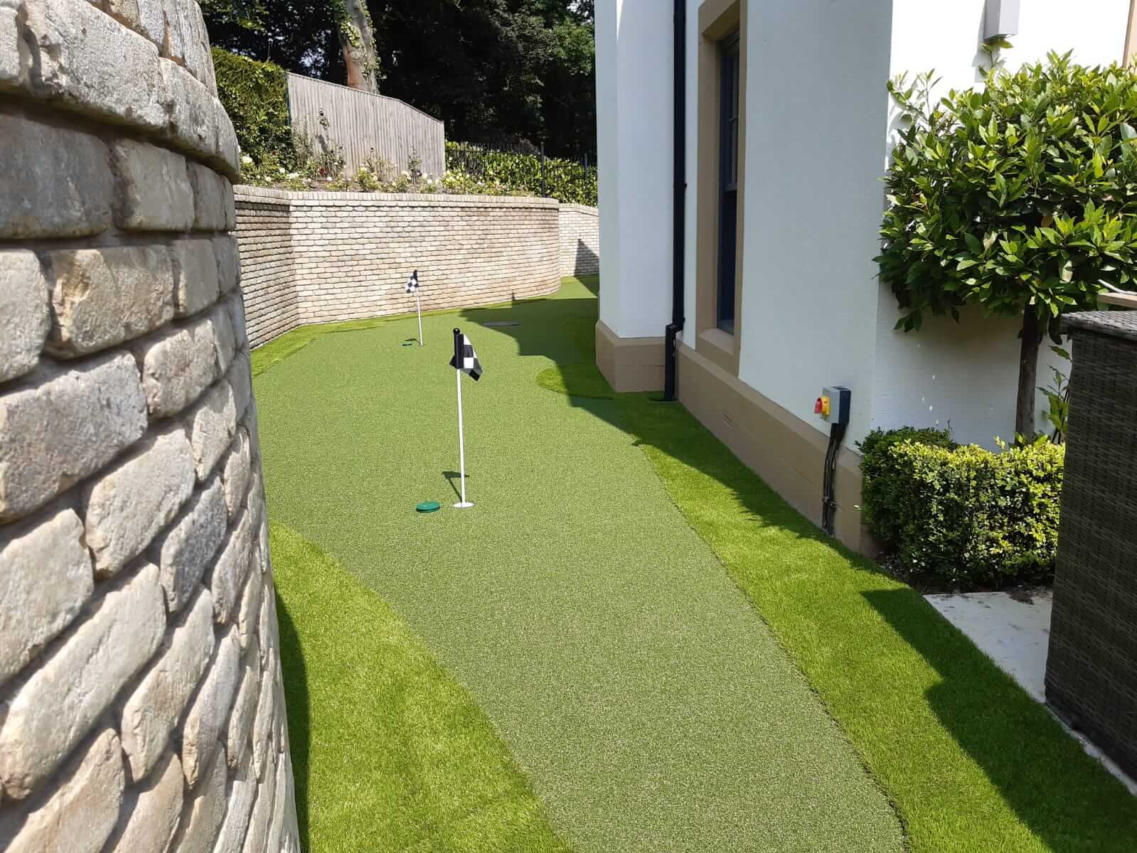 Photo of a 9 hole garden putting green going down the side of the house.