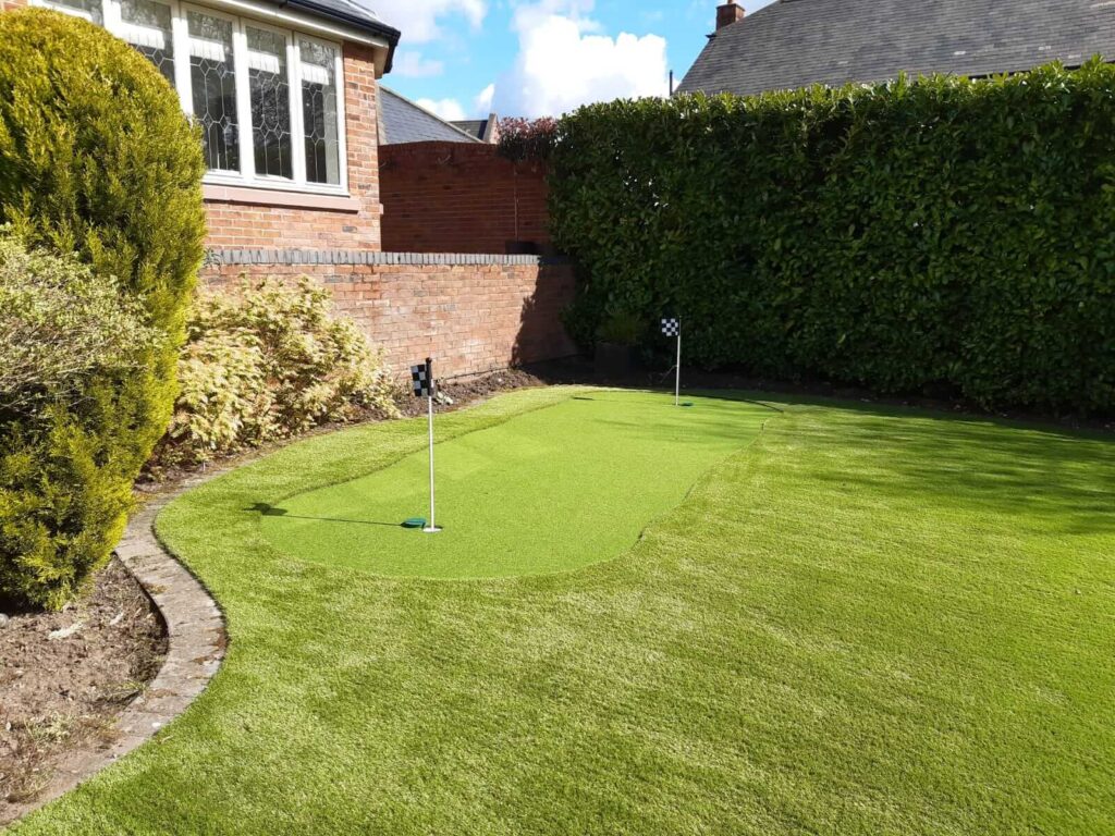 Photo of a large garden with artificial grass and a small, two hole putting green in the corner. 