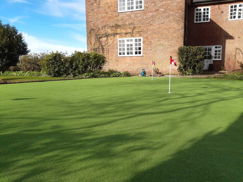 Photo of a large garden with a artificial grass putting green installed with flags and holes. 