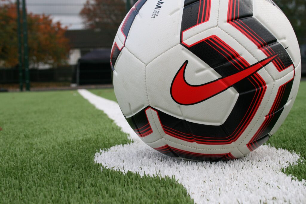 Photo of a close up of the artificial football pitch centre line with a football on it.