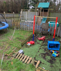 Messy garden with old climbing frame and a patch of artificial grass